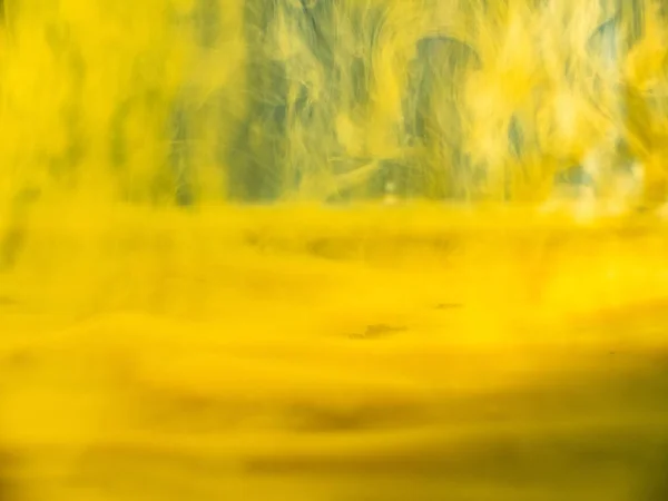 水の下で渦巻く黄色の塗料、抽象的な背景。ビューを閉じます。背景がぼやけている。選択的ソフトフォーカス。液体、抽象的なパターンと混合黄色のアクリル塗料の流れ。抽象美術. — ストック写真