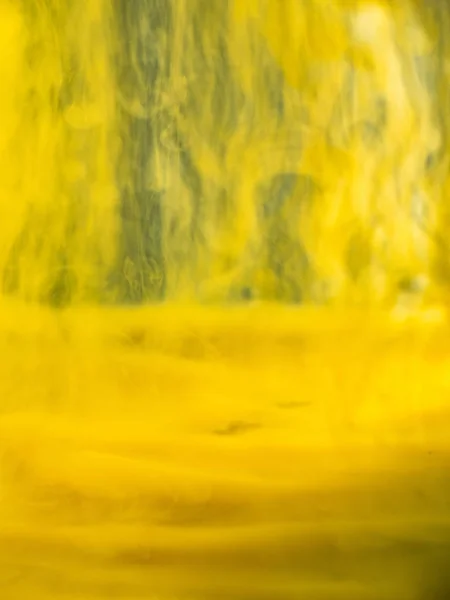 液体中の黄色の塗料の抽象的な流れ。ビューを閉じます。ぼやけた背景。選択的なソフトフォーカス。黄色のアクリルインクが水に落ちた、抽象的な背景。水とインク混合、抽象的なパターン. — ストック写真