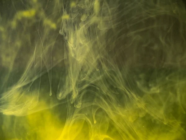 Fumo acrilico giallo sott'acqua, vista da vicino. Sfondo sfocato. Goccia di inchiostro giallo che si dissolve in acqua, sfondo astratto. Vernice acrilica miscelazione con liquido, sfondo astratto . — Foto Stock