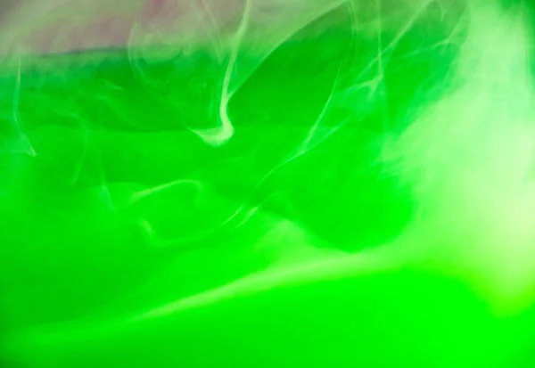 Green acrylic clouds under water, abstract blurred background. Close up view. Green paint dropped into water, abstract pattern. Acrylic ink dissolving into liquid. Background for abstract banners.