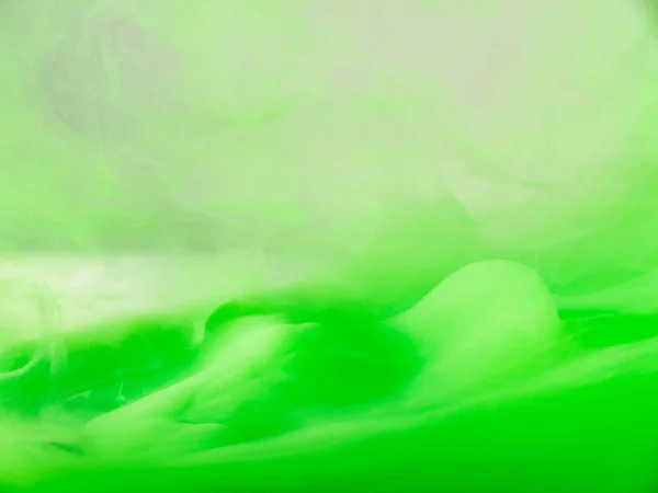 Зеленые акриловые облака движутся под водой, абстрактный размытый фон. Крупный план. Чернильные облака кружатся в жидком, абстрактном рисунке. Капли зеленых чернил растворяются в воде. Краска в жидкости . — стоковое фото