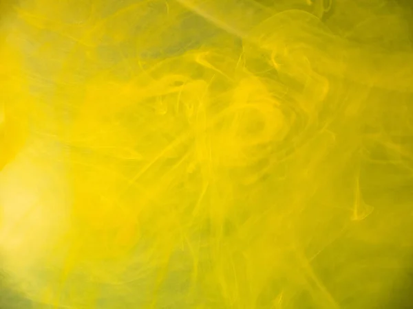 Yellow abstract smoke under water, blurred background. Close up view. Yellow paint dropped into water, abstract pattern. Paint dissolving into liquid, abstract background. Ink mixing with liquid. — Stock Photo, Image