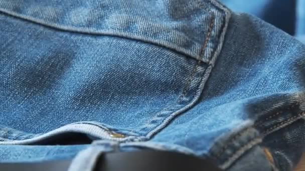 Blue jeans, close shot. Blurred background. Selective soft focus. Camera moving along rear trouser pockets and leather belt. Background for fashion wallpapers. Clothing for everyday wearing. — Stock Video