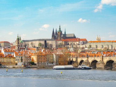 Prag, Çek Cumhuriyeti - Nisan 2019: Moldau nehrinden St. Vitus Katedrali'nin tepesine ve Charles Köprüsü'nün bir kısmına bak. Köprüye yakın bir tekne yelkenli. Prag'ın gotik mimarisi.