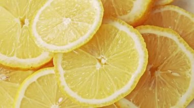 Sarı limon dilimleri yığını, yakın çekim. Rotatif arka plan. Limon dilimlerinin soyut deseni. Sarı sulu meyvelerin bileşimi. Limon yapısı. Seçici yumuşak odaklama.
