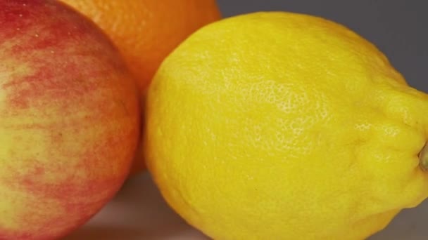 Közeli lövés a friss gyümölcsök. Rotative háttér. Telepítése piros alma, sárga citrom és narancs. Trópusi gyümölcsök csendélet. Szelektív lágy fókusz. Elmosódott háttér. — Stock videók