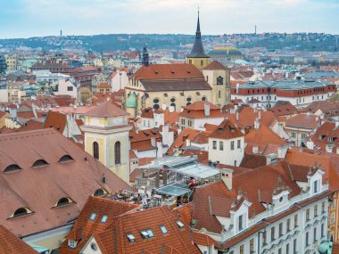 Prag, Çek Cumhuriyeti - Nisan 2019: Kuşlar açısından vintage şehir. Prag'da antik binanın çatısında turistlerin yer alan açık hava kafe. Turuncu çatılar ve ağaçların yeşil üstleri ufukla birleşiyor.