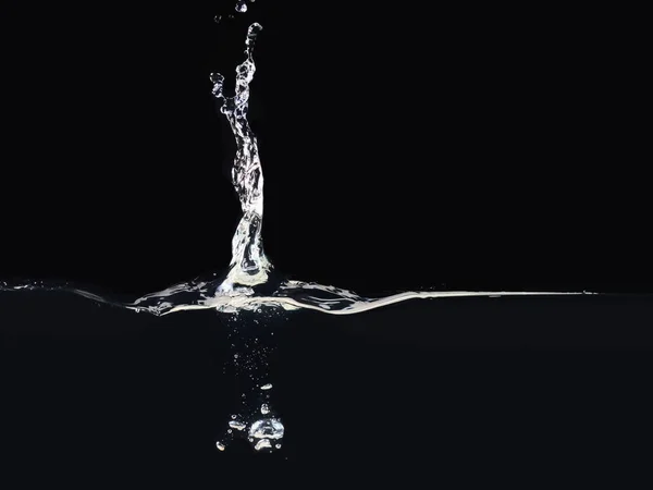 Stänk på vattenytan isolerad på svart bakgrund, närbild. Droppe faller i vätska. Bubblor under vattnet. Redo att använda blandningsläge till skärmen eller lägga till. — Stockfoto