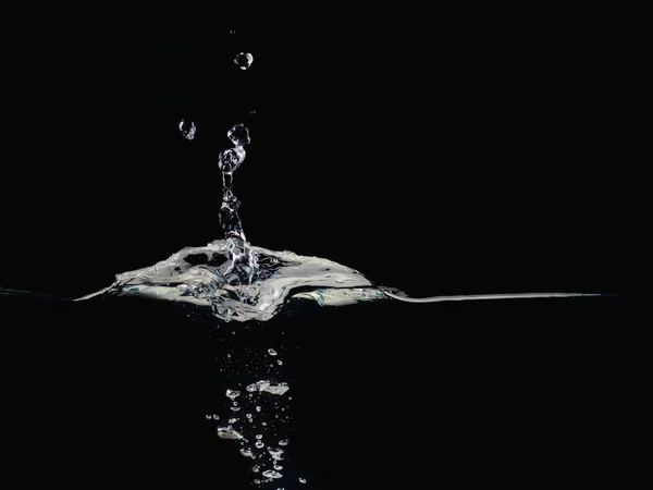 Drop of water splashes on surface making bubbles and rippling, isolated on black background, close up view. Perfect to compositing into your shots. Ready to use blending mode to screen or add.