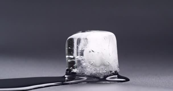 Таяние кубического льда. Видео снято крупным планом. Видео хронометража. Тающий куб льда на чёрном фоне. — стоковое видео