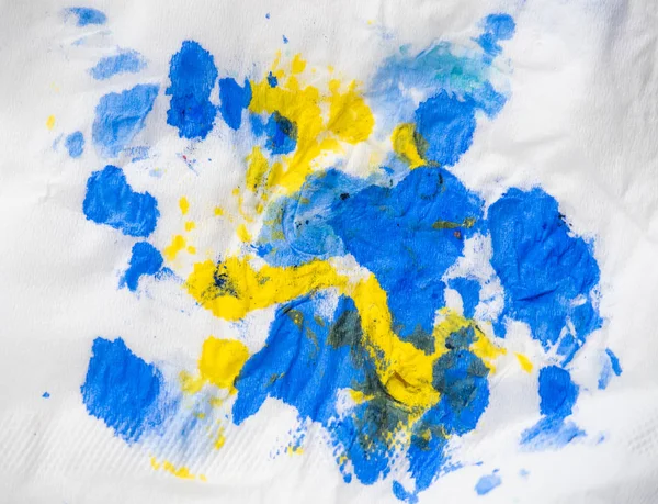 Abstract background. Yellow and blue color spots on white paper, close up view. Inkblots on white background. Abstract drawing. Paint blotch on white.