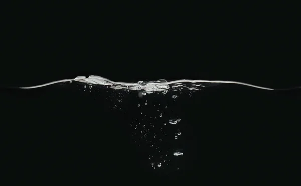 Waving water surface and small bubbles underwater isolated on black background, close up view. Perfect for compositing into your shots. Ready to use blending mode to screen or add.