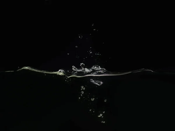 Splash on water surface makes waves and water bubbles isolated on black background, close up view. Perfect for compositing into your shots. Ready to use for blending mode to screen or add.