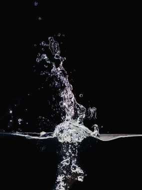 Siyah arka plan üzerinde izole yüzeyde su sıçraması, görünümü kapatın. Küçük su kabarcıkları su altında ve havada. Bindirmeler tasarımı, ekran karıştırma modu katmanı için soyut arka plan.