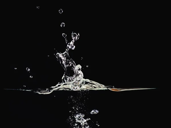 Acqua spruzzata, superficie increspata, bolle d'acqua nell'aria e sott'acqua, isolata su fondo nero, vista da vicino. Sfondo nero astratto per sovrapposizioni di progettazione, livello di modalità di fusione dello schermo . — Foto Stock