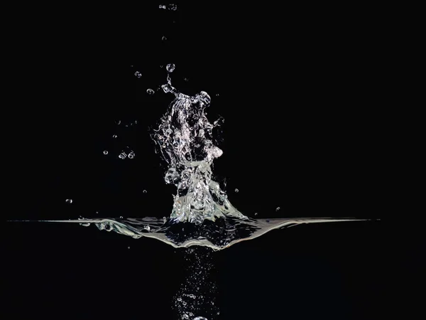 Wasserexplosion auf flüssiger Oberfläche isoliert auf schwarzem Hintergrund, Nahaufnahme. Wellenfläche, Wasserblasen, Spritzwasser, abstrakter schwarzer Hintergrund für Overlays-Design, Bildschirmmischmodus-Ebene. — Stockfoto