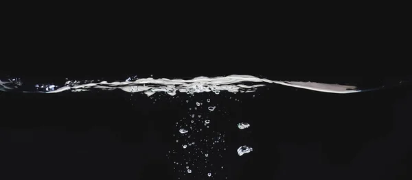 Waving liquid surface isolated on black background, close up view. Small water bubbles underwater. Black abstract background for overlays design, screen blending mode layer. — Stock Photo, Image