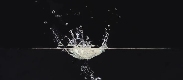 Water splash on liquid surface isolated on black background, close up view. Water bubbles in air, abstract black background for overlays design, screen blending mode layer.