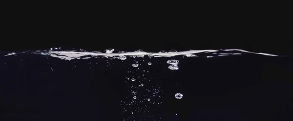 Bolle d'acqua isolate su fondo nero, vista da vicino. Rippling superficie liquida, uno sfondo astratto per la progettazione sovrapposizioni, strato modalità di miscelazione dello schermo . — Foto Stock