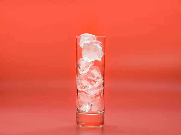 Vidrio lleno de cubitos de hielo sobre fondo rosa, vista de cerca. Trozos de agua sólida en vidrio fotografiados mientras se derrite. Enfoque suave selectivo. Fondo borroso . —  Fotos de Stock