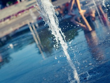 Kuru Çeşme içinde sıçramaya su damlaları yakın görünüm. Çocuk çıplak ayak Çeşme yakın yürüyüş. Kuru çeşme ile yaz Cityscape. Seçmeli yumuşak odaklama. Bulanık arka plan.