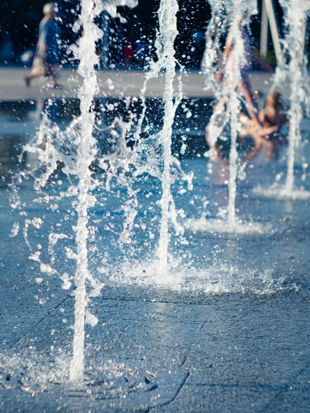 Gotas de agua de la fuente seca salpicaduras en el recubrimiento cuadrado de granito, vista de cerca. Niños enfriándose en aerosoles de agua. Paisaje urbano de verano. Enfoque suave selectivo. Fondo borroso . —  Fotos de Stock