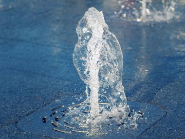 Dikey su akışı kuru Çeşme Paslanmaz ızgara dışarı akan, görünüm yakın. Paslanmaz kaplama üzerine su akışı sıçraması. Seçmeli yumuşak odaklama. Bulanık arka plan.