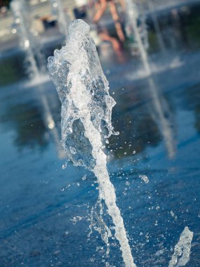 Dere ve su damlaları kare granit kaplama üzerine sıçrayan, görünümü kapatın. Çocuklar kuru çeşme nin yanında çıplak ayaklar. Yaz şehir manzarası. Seçici yumuşak odak. Bulanık arka plan.