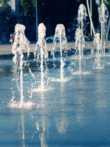 Línea de arroyos de agua de fuente seca en la plaza principal de la ciudad, vista de cerca. Flujos de agua que salen de la rejilla de acero inoxidable. Paisaje urbano de verano. Enfoque suave selectivo. Fondo borroso . —  Fotos de Stock