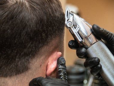 Stilist kesme mans saç makas ile, yakından görünümü. Eller siyah lastik eldivenler makas ile çalışıyor. Kuaför salonuiş iş başında kuaför. Seçici yumuşak odak. Bulanık arka plan.