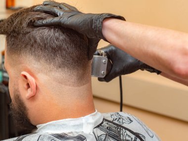 Stilist müşterilerine ense tutan ve makas ile saç kesme, yakın görünümü. Stilistler elleri siyah lastik eldivenler. Kuaför salonunda saç kesme işlemi. Seçici yumuşak odak. Bulanık arka plan.