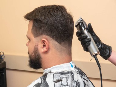 Stilist makas ile saç kesme, yakın görünümü. Ustalar siyah lastik eldivenler içinde elleri. Berber dükkanında fotoğraflandı. Seçici yumuşak odak. Bulanık arka plan.