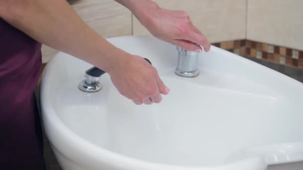 Vrouw opent het water in de wasstand in Barbershop. Kapper wassen handen in wastafel, close-up uitzicht. Selectieve zachte scherpstelling, onscherpe achtergrond. — Stockvideo