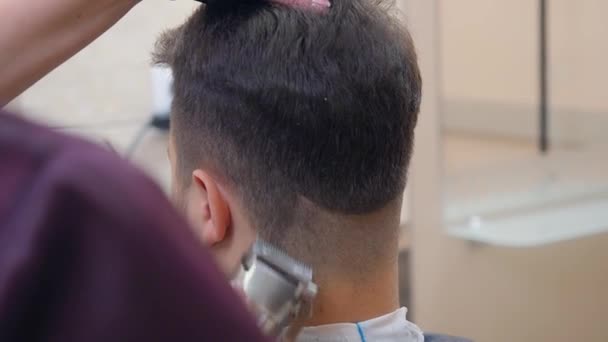 发型师剪男性头发与剪子和梳子，近距离拍摄。记录在理发店。大师在海服轿车工作。选择性软焦。模糊背景. — 图库视频影像