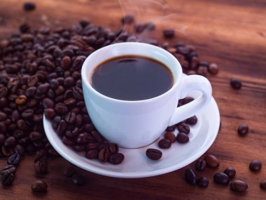 Kahve çekirdeklerinin bileşimi kahverengi masa ve çay tabağı dolusu espresso ile birlikte. Ahşap masa dokusu. Seçici yumuşak odaklanma. Bulanık arkaplan.