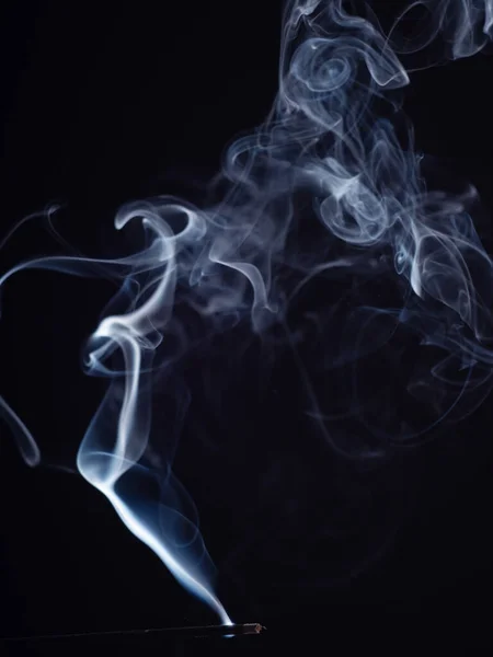 Burning incense isolated on black background, close up view. Structure of smoke, brush effect. Abstract background of smouldering incense stick. Fragrance for meditation and relaxation. — ストック写真