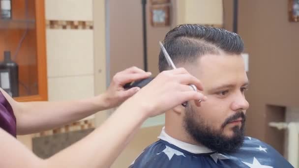 Cabeleireiro corte homem cabelo com tesoura e pente, tiro de perto. Mestre no trabalho no salão de cabeleireiro. Interior da barbearia. Foco suave seletivo. Fundo desfocado . — Vídeo de Stock