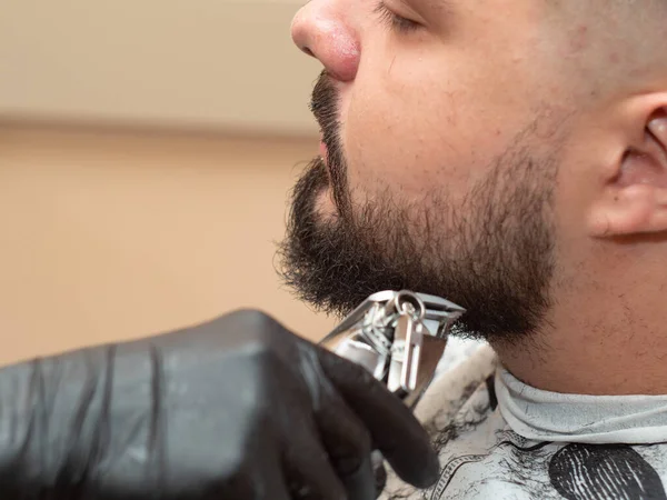 Estilista corte castor machos con clipper, vista de cerca. Manos en guantes de goma negros. Hombre en peluquería. Enfoque suave selectivo. Fondo borroso . —  Fotos de Stock