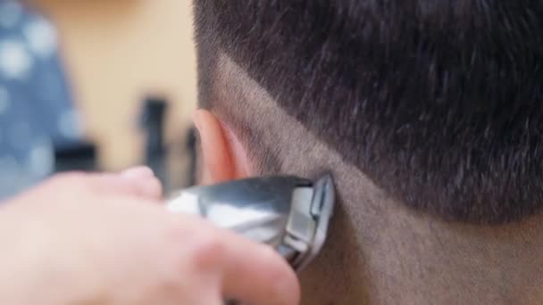 Capelli da taglio Master con clipper e pettine, colpo ravvicinato. Maschi nuca vicino. Registrato nel salone di parrucchiere. Concentrazione selettiva morbida. Sfondo sfocato . — Video Stock