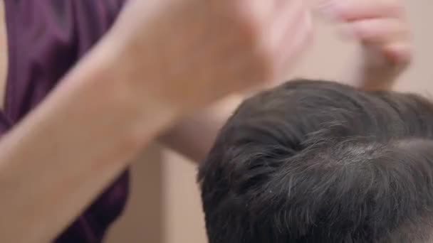 Proces stříhání vlasů, těsný záběr. Mistr stříhání klientů vlasy s černým hřebenem a nůžkami. Muž v holičství. Selektivní měkké zaměření. Rozmazané pozadí. — Stock video