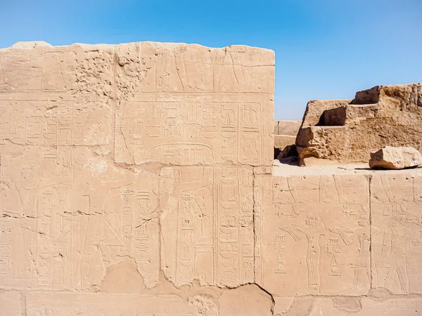 Ancient paintings and inscriptions on ruined wall in Karnak temple, medium view. Photographed in Luxor, Egypt. Selective soft focus. Blurred background.