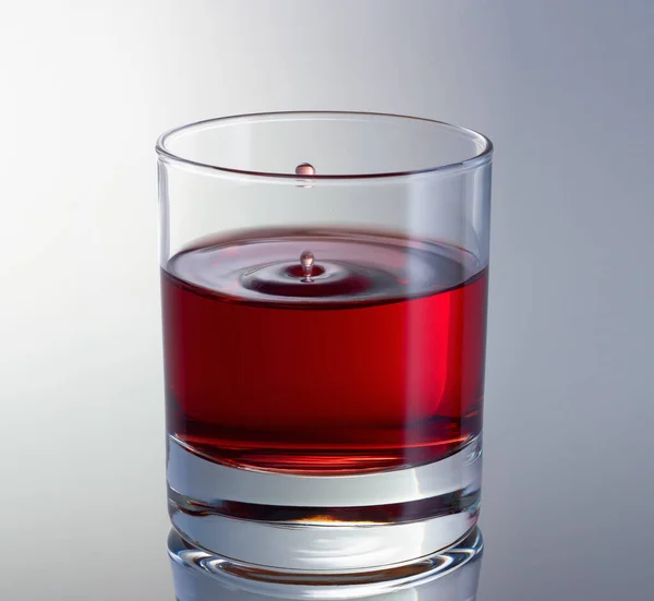 La goccia sta schizzando nel vetro. Goccia di vino rosso aleggiava nell'aria. — Foto Stock