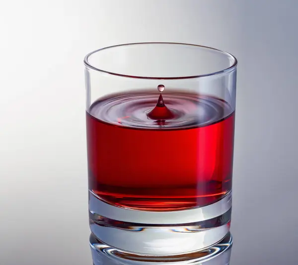 Ein Tropfen Rotwein im Glas aus nächster Nähe. Hochgeschwindigkeitsschuss. Wellen im Glas — Stockfoto