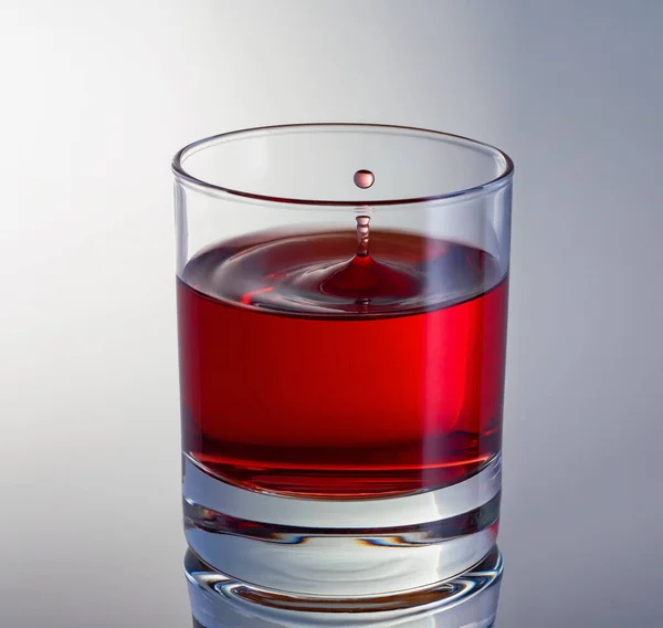 La pila di gocce di vino che vola in vetro di vino rosso da vicino. Colpo ad alta velocità. — Foto Stock