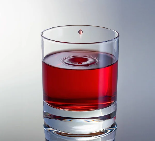 Goccia di vino aleggiava nel bicchiere. Imbuto sulla superficie del vino. Bicchiere di vino rosso da vicino. Colpo veloce. — Foto Stock