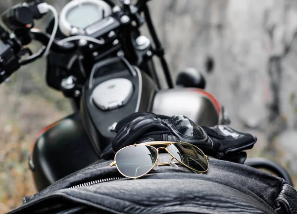 sunglasses and gloves on the background of a motorcycle fuel tank