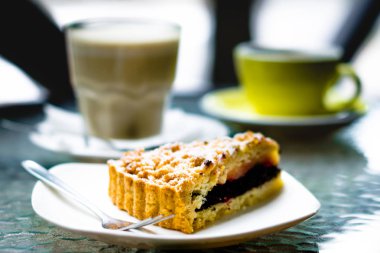 üçgen parça haşhaş pasta ve bir çatal ile bir arka plan beyaz kahve ve sarı bir kupa ile şeffaf cam üzerine pudra şekeri