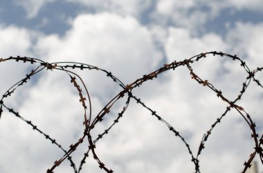 mavi gökyüzü ve beyaz bulutlar karşı eski paslı dikenli tel çit