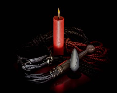 bdsm rope with a red burning candle and a lash with a leather collar on a dark background clipart