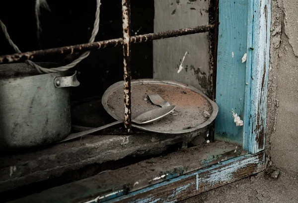 Vecchi piatti di metallo sporco su una finestra con un reticolo arrugginito — Foto Stock